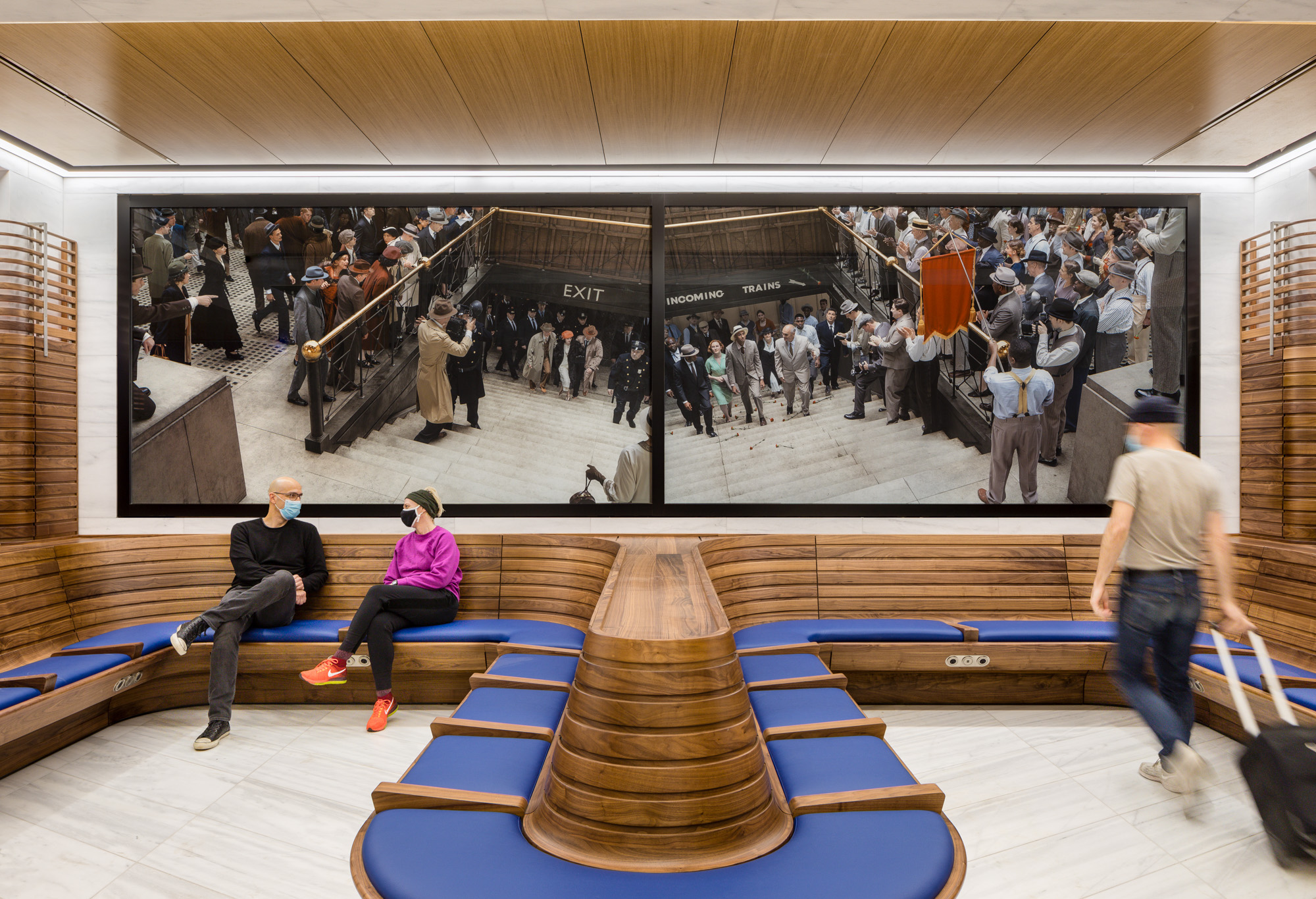 Two horizontal panels of photographs, with blue upholstery and wood seating below the panels. The two photographs depict reenactments of significant but little-known...