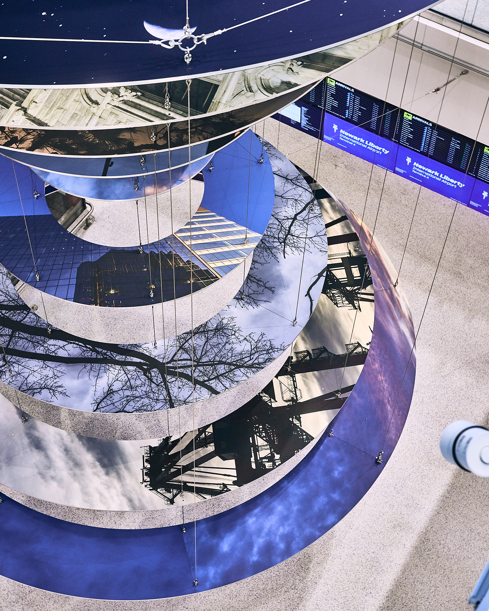Slices of New Jersey skyline photographs are suspended in two large helix-like structures, hanging from the inside of an airport terminal.