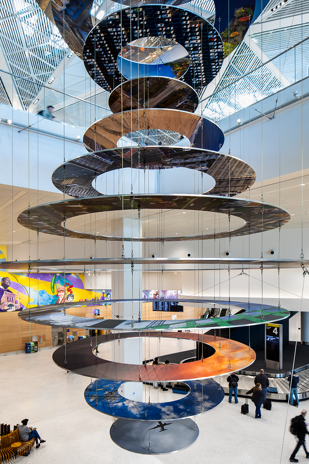 Slices of New Jersey skyline photographs are suspended in two large helix-like structures, hanging from the inside of an airport terminal. Behind the sculpture...