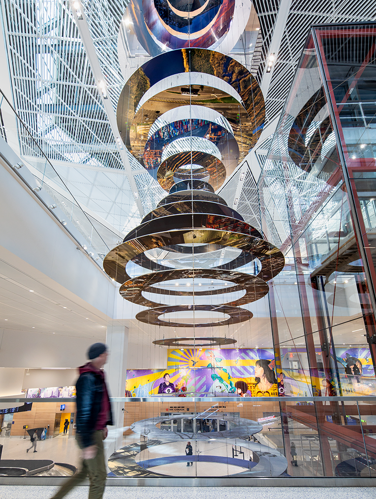 Slices of New Jersey skyline photographs are suspended in two large helix-like structures, hanging from the inside of an airport terminal. Behind the sculpture...