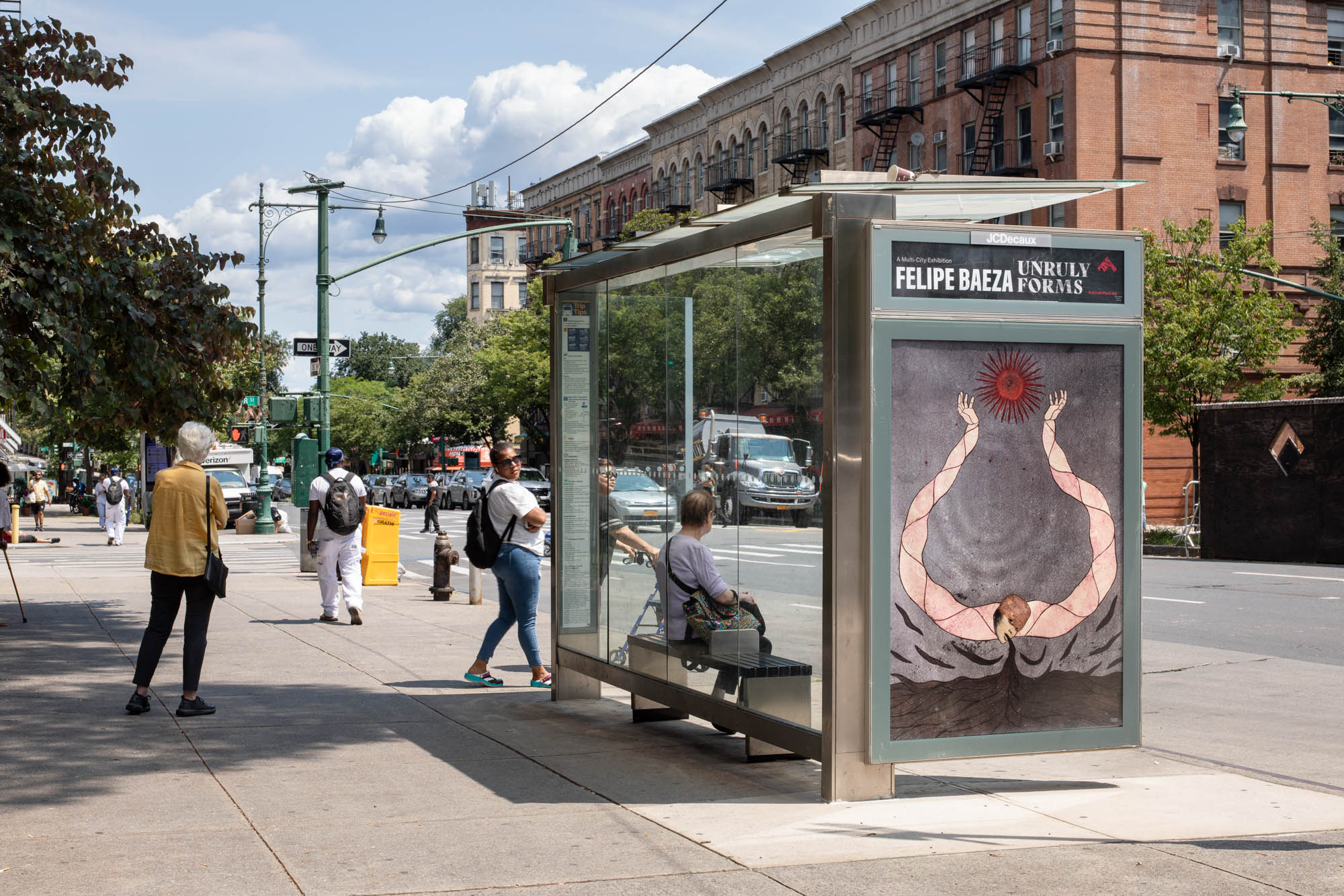 Pictured on a bus shelter on a busy city street is a layered hybrid figure that merges human, artifact, animal, and vegetation.