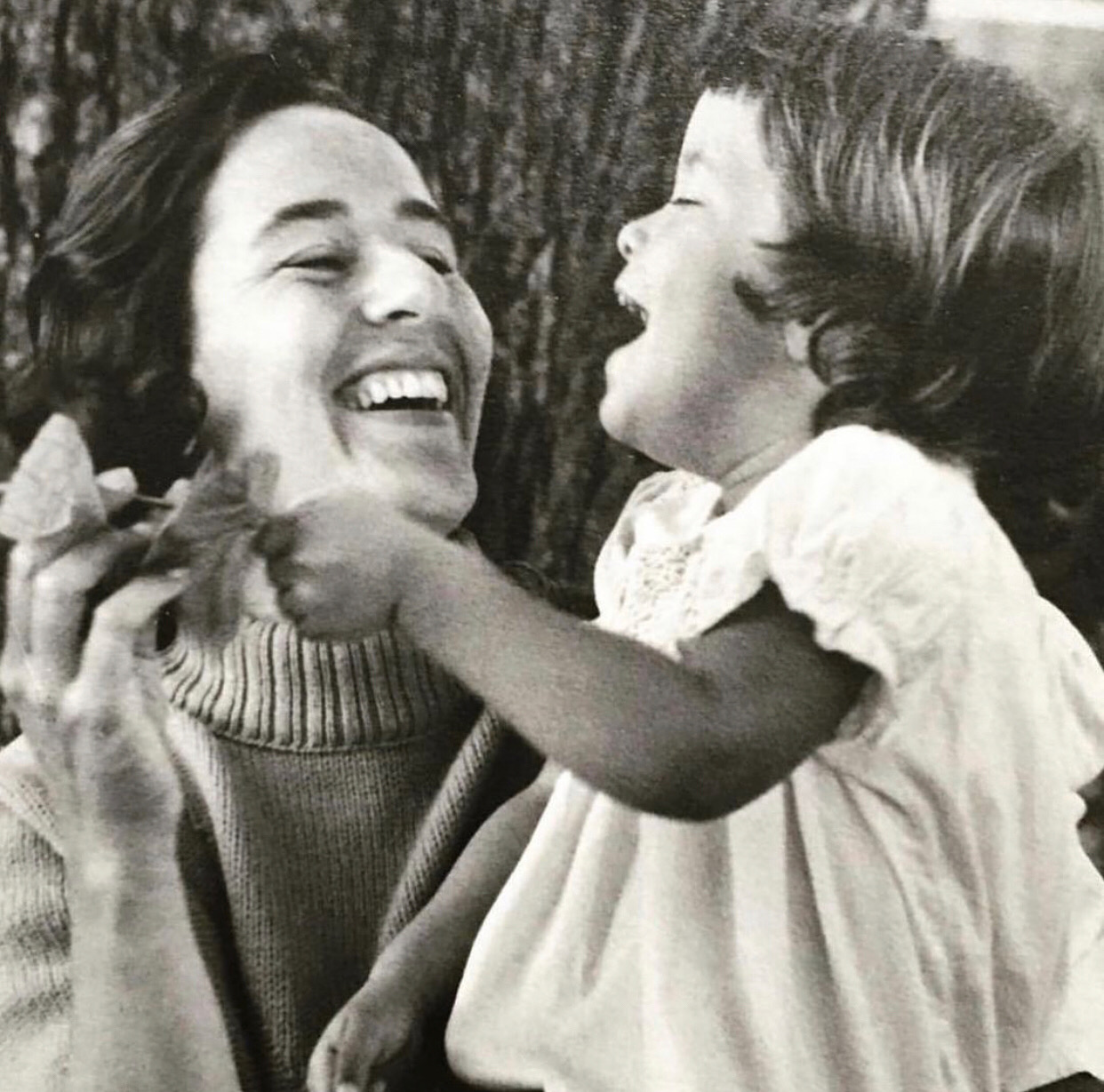 A black and white photograph of a mother and a daughter laughing together.